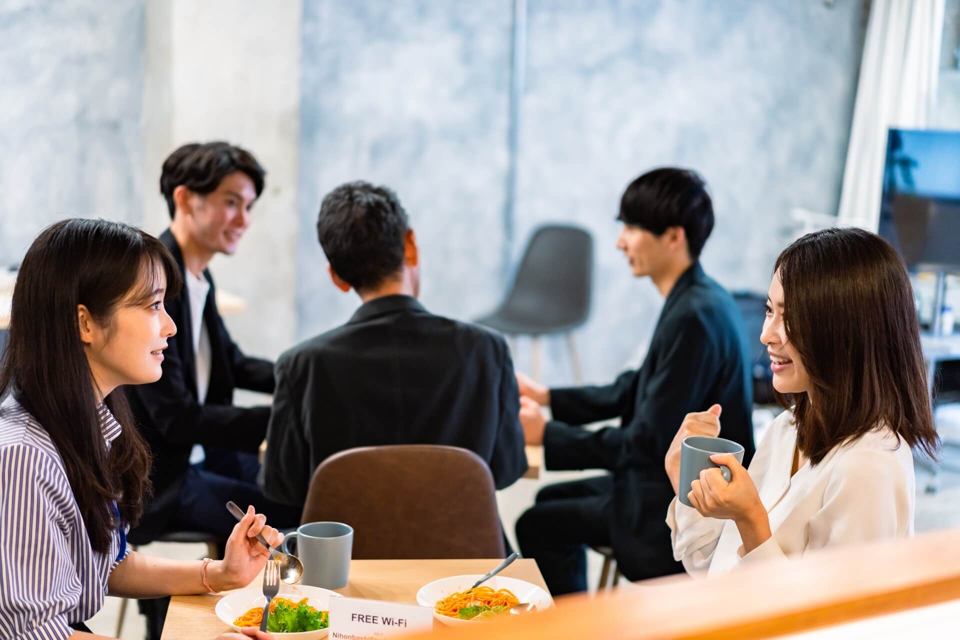 明るい雰囲気の社員食堂でランチを取るオフィスワーカー